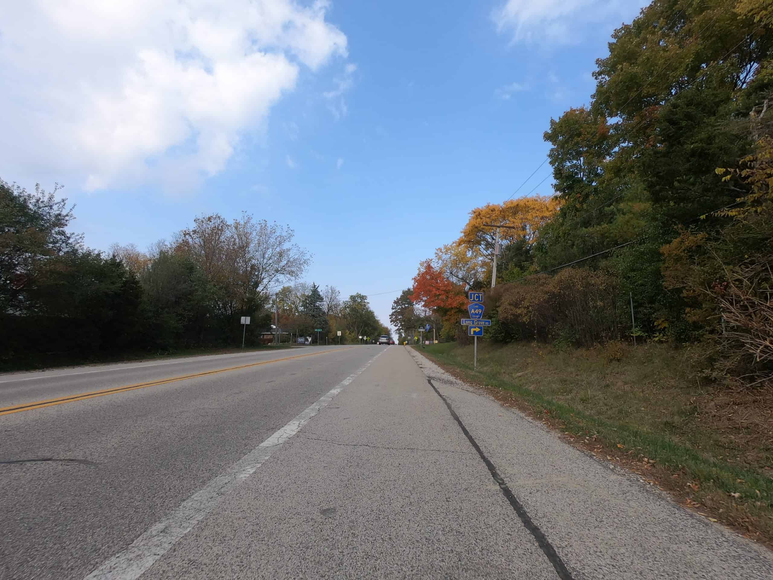Looking down a colorful tree lined two-lane road.