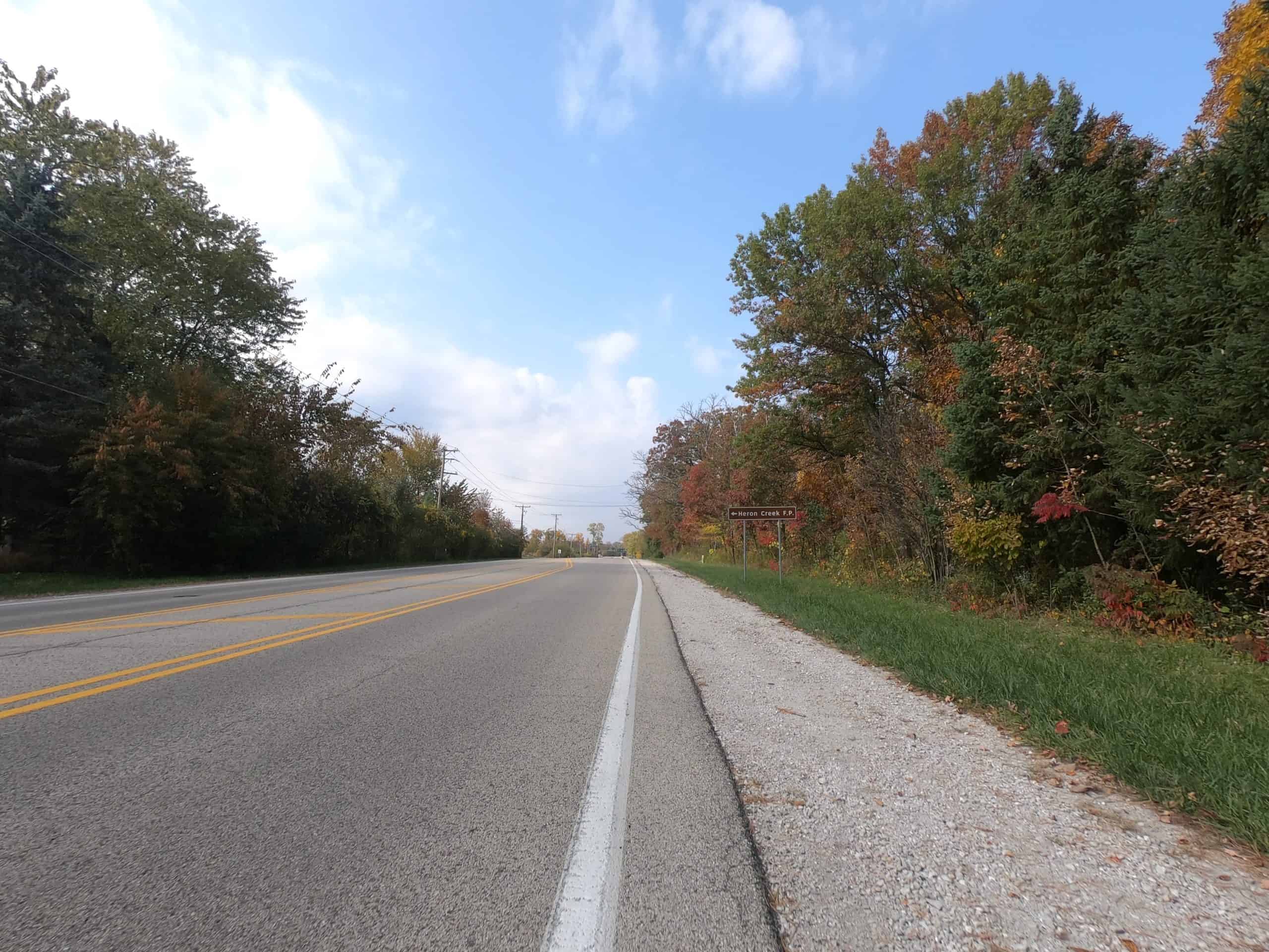 Looking down a colorful tree lined two-lane road.