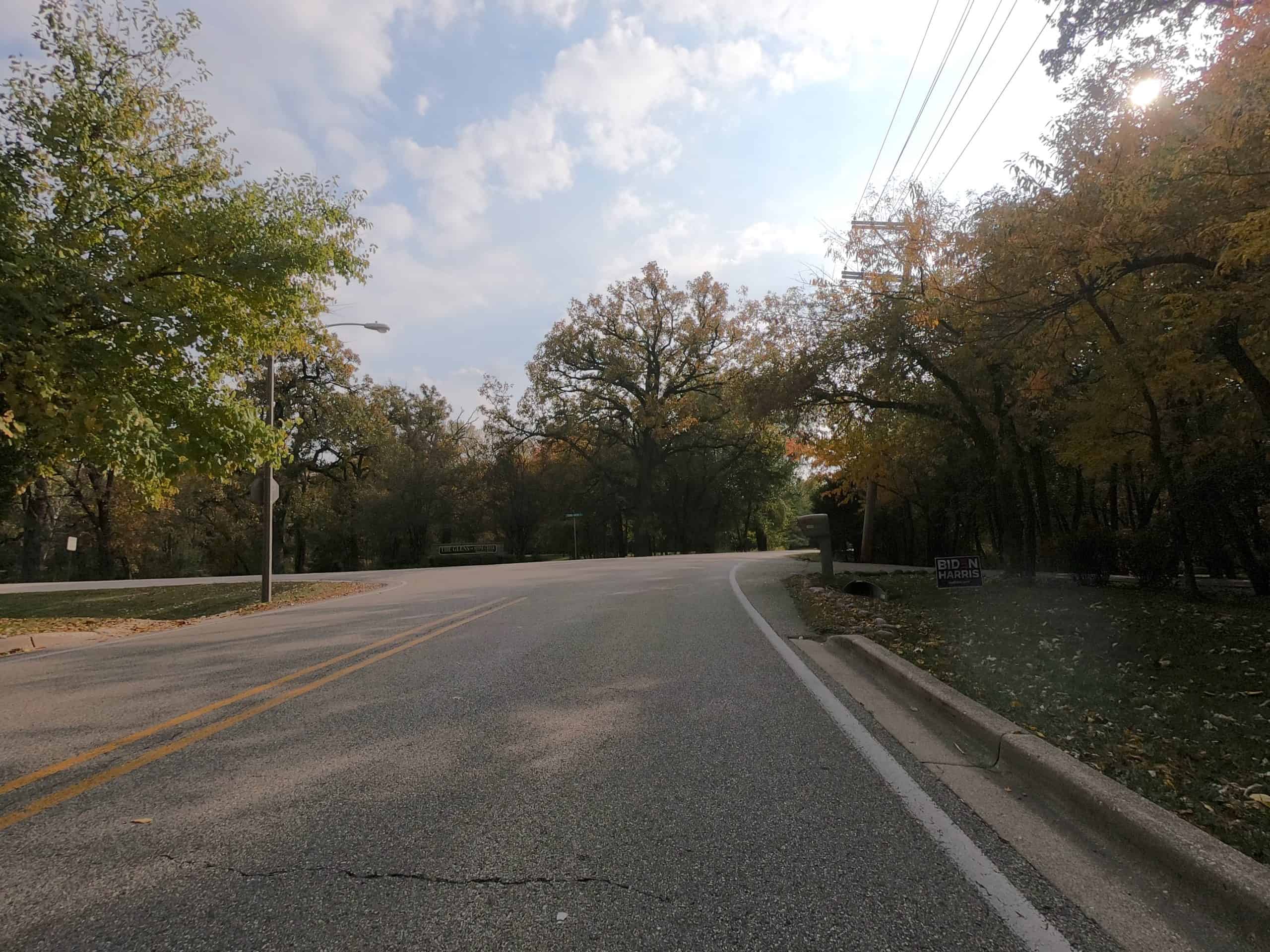 Looking down a colorful tree lined two-lane road at a T intersection with another road.