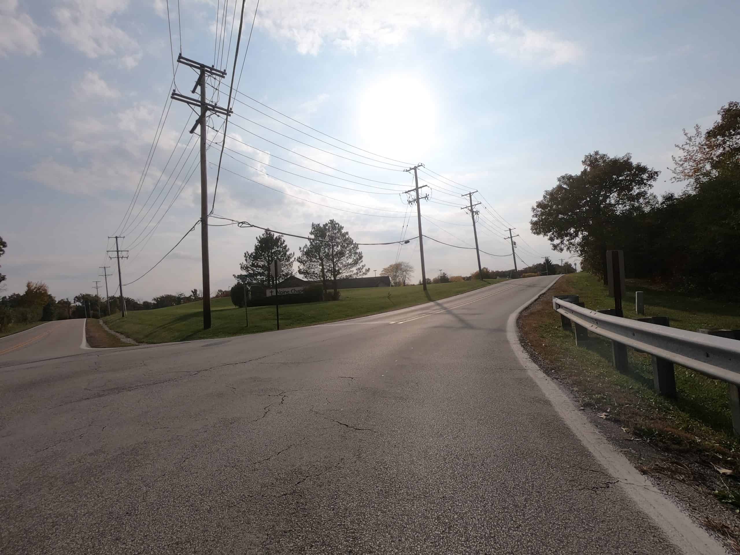 Looking down a colorful tree and meadow lined two-lane road.