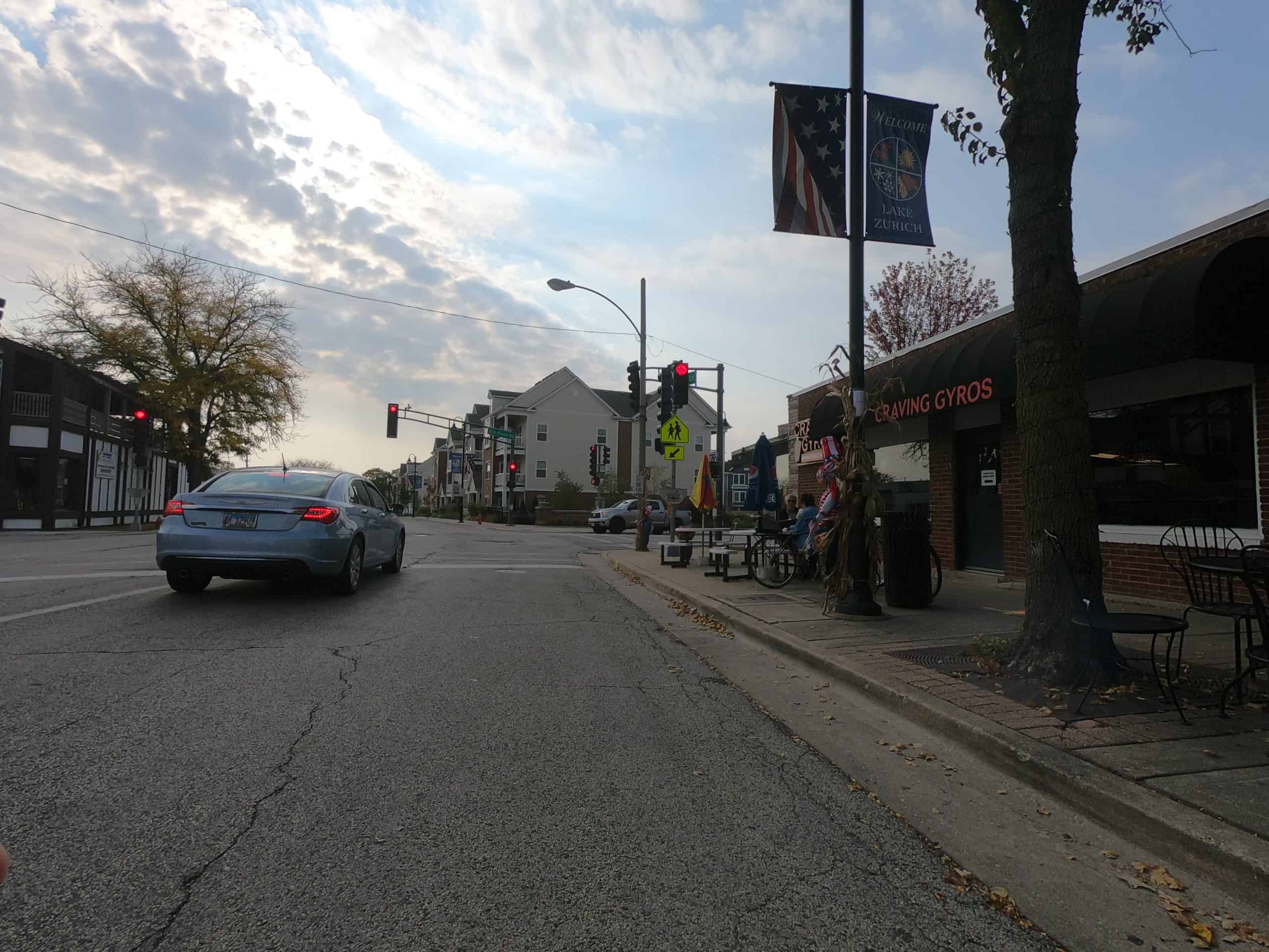 Looking down a street at a small-town downtown intersection with a red light and car.