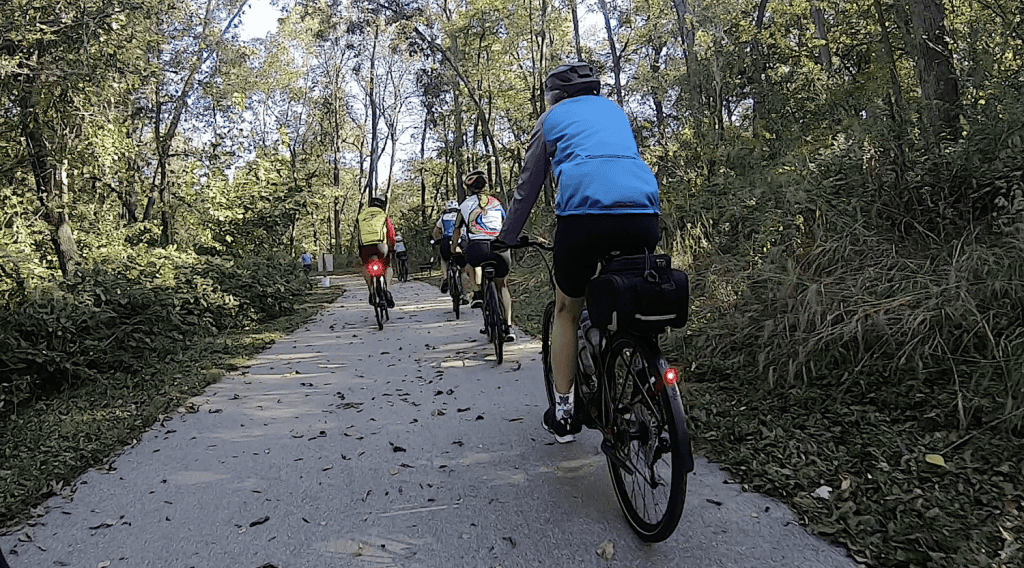 Colorful group cycling through suburban Chicago forest trail.
