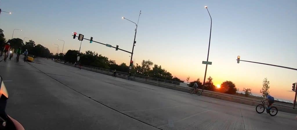 The sun rises over Lake Michigan in the background as we turn onto a car-free Lake Shore Drive with other cyclists.