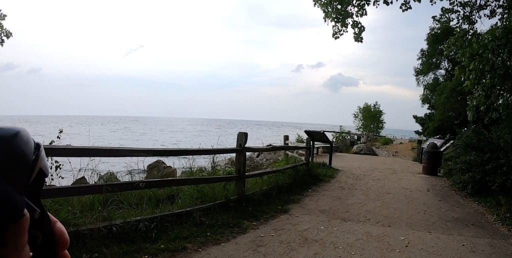 Looking down a path to a beach in the distance, with Lake Michigan on the left under gray but bright clouds.