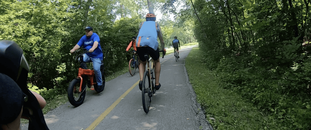 Looking ahead on a two-lane paved bike trail with bicyclists in front of us in both directions.