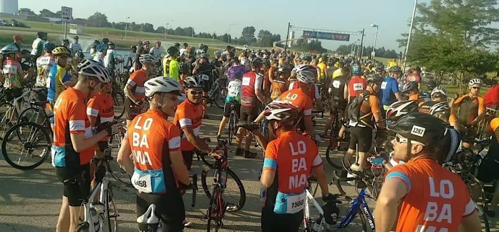 A large group of cyclists in summer at the starting line of a bike ride in the country.