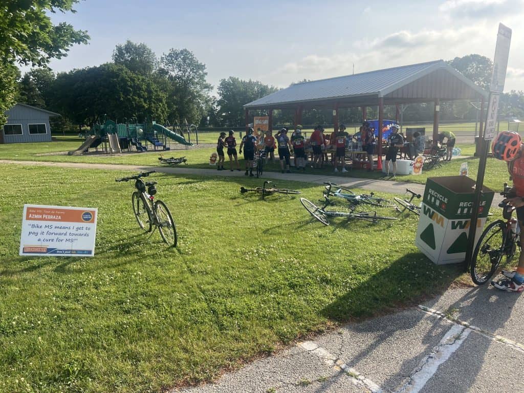 Looking at a shelter full of cyclists from afar with a Bike MS sign and a few bicycles up front.