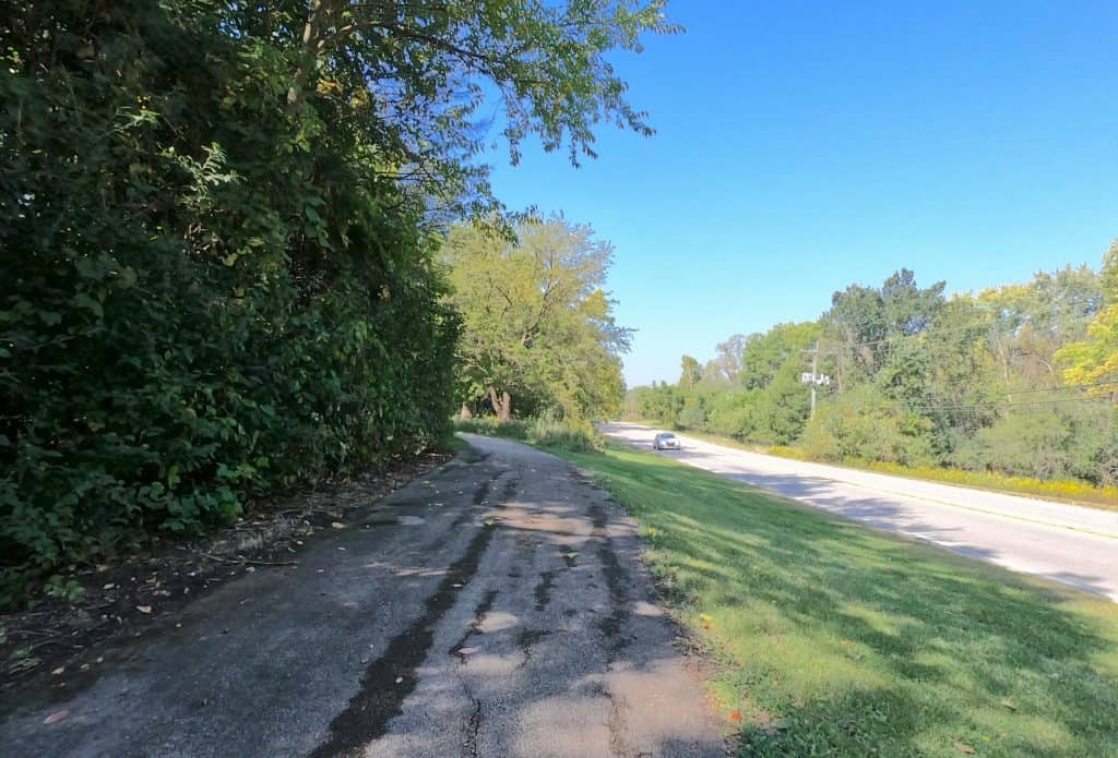 Secluded bike trail in suburban Chicago with lush greenery and clear blue skies, perfect for cycling enthusiasts seeking scenic outdoor routes.