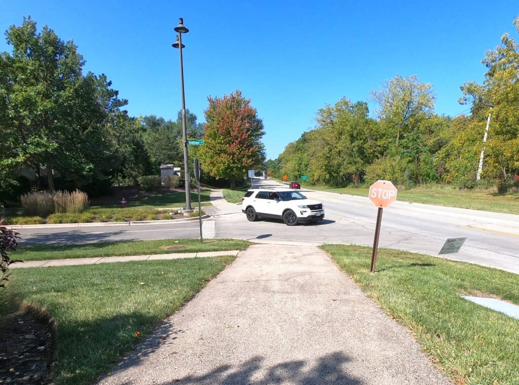 A suburban sidewalk crossing with a stop sign and street view, ideal for suburban Chicago bicycling and pedestrian safety.