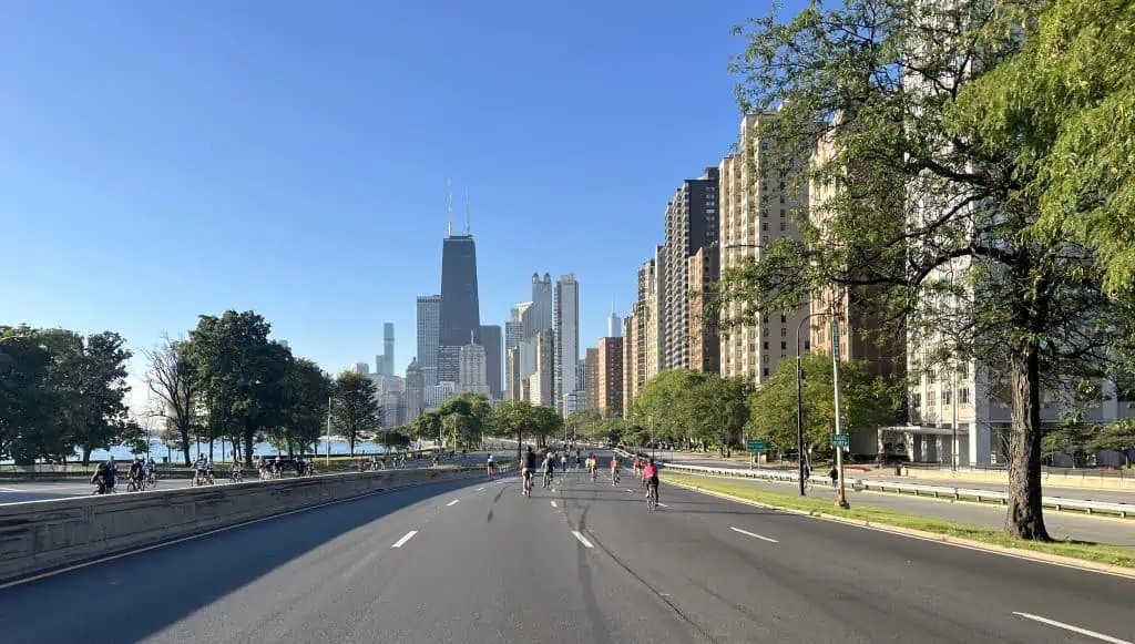 Beautiful view of downtown Chicago skyline with cyclists riding along Lake Shore Drive during daytime.