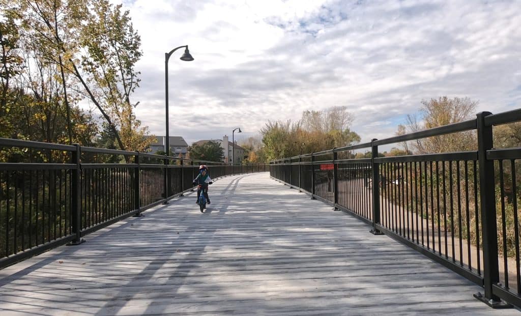 A young child riding a bicycle on a scenic bridge in suburban Chicago.