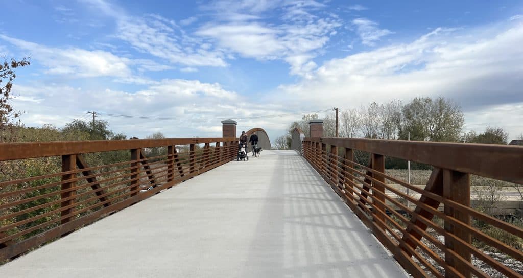 Scenic suburban Chicago bike trail with bridge and cyclists enjoying outdoors.