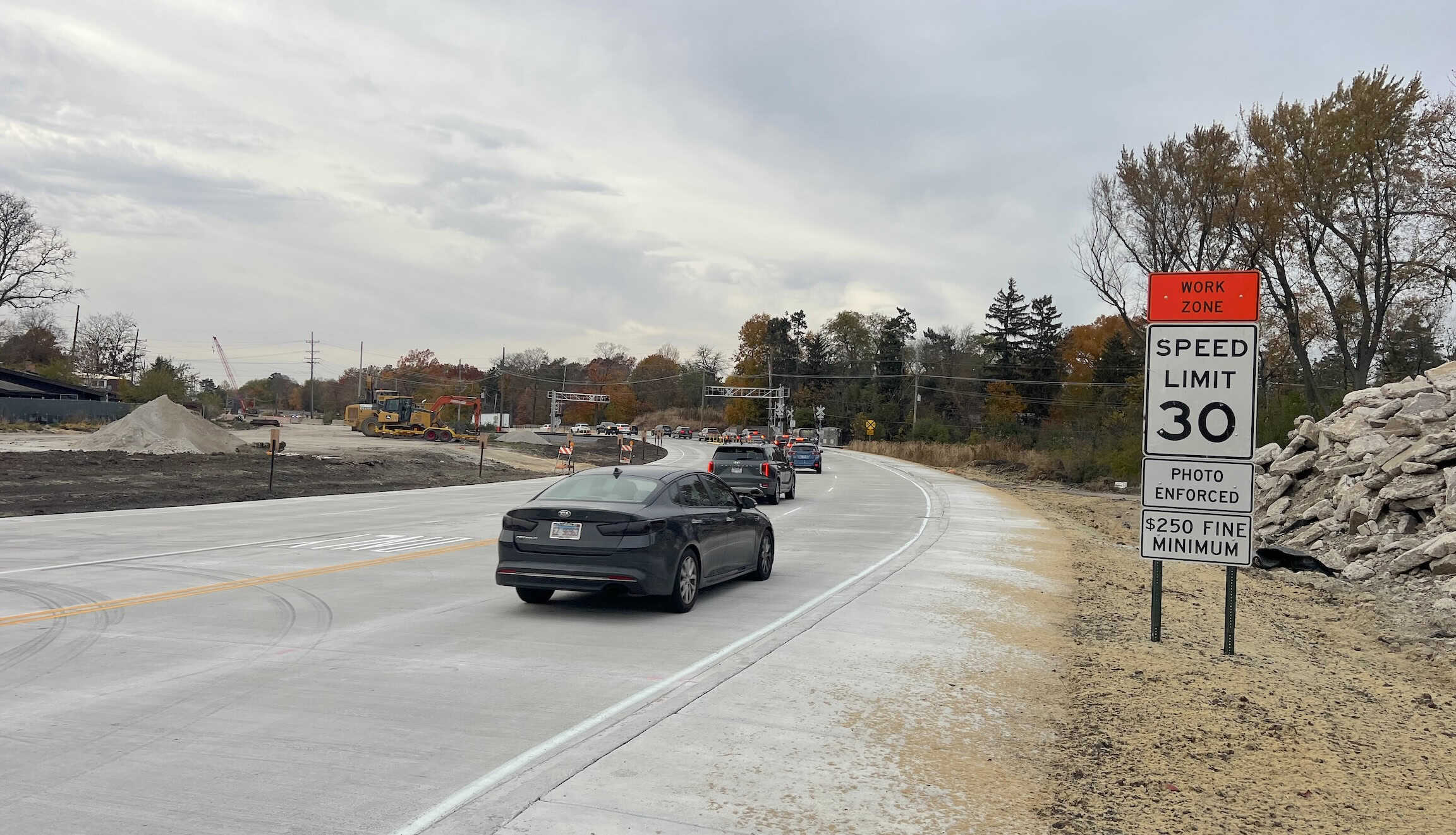 Construction zone on suburban Chicago street with cars, speed limit, and work zone sign.