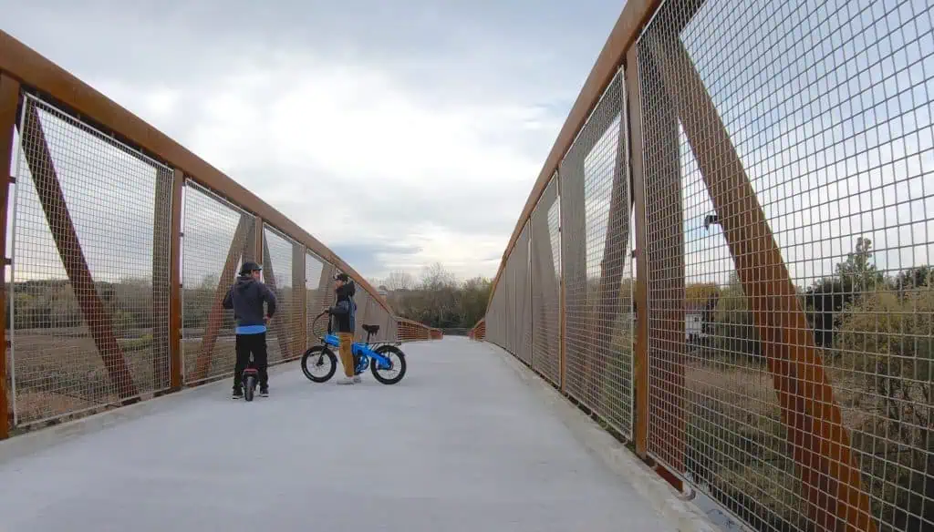 People riding bikes on a metal bridge in suburban Chicago.