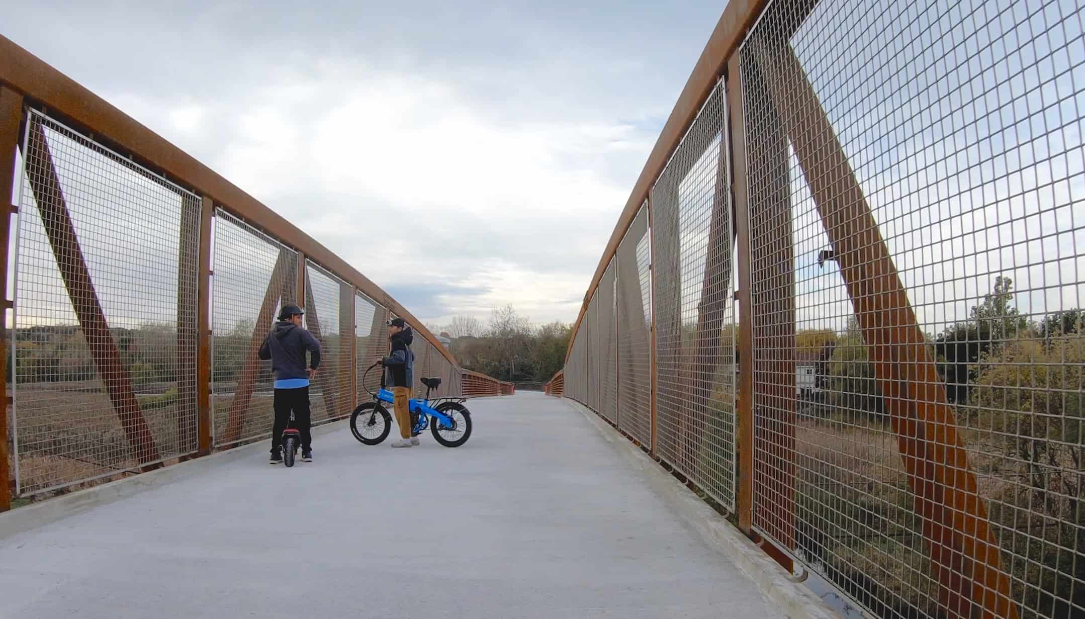 People riding bikes on a metal bridge in suburban Chicago.