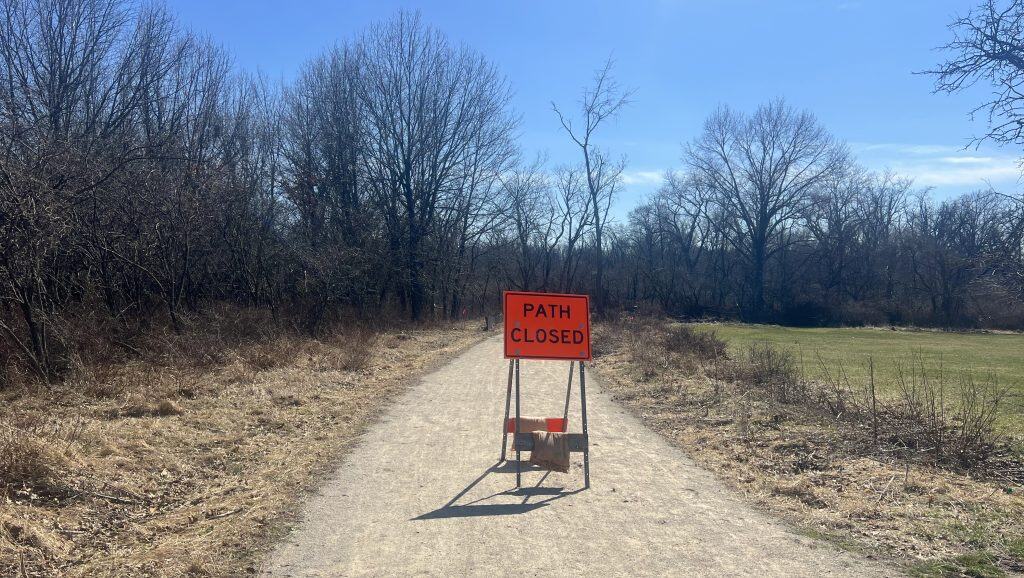 Closed trail path on a forest bike trail in suburban Chicago with a "Path Closed" sign.