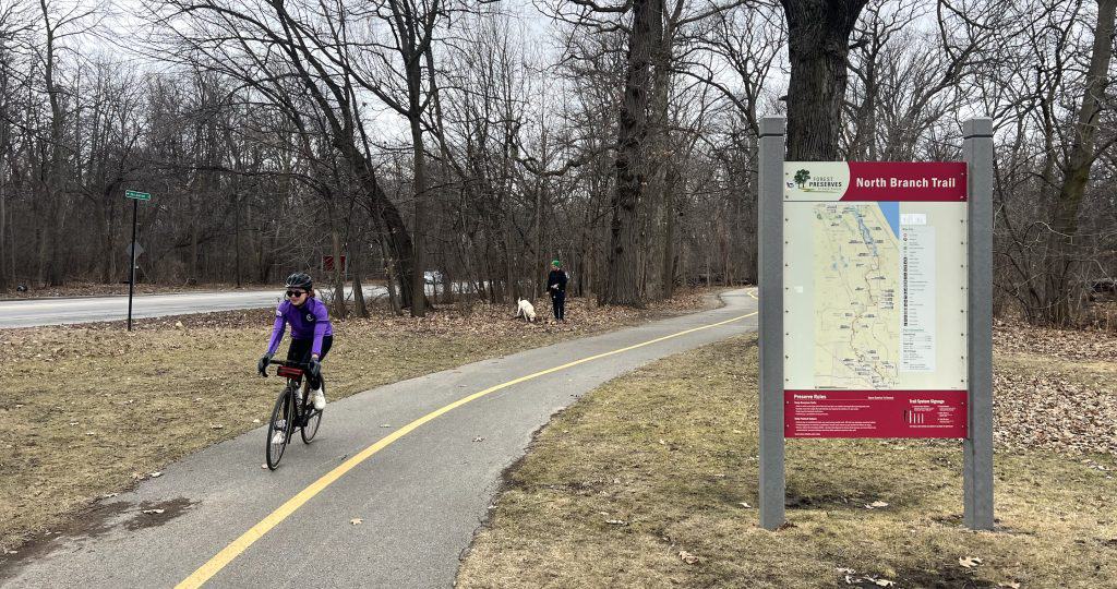 Biking on North Branch Trail in suburban Chicago with trail map in background.
