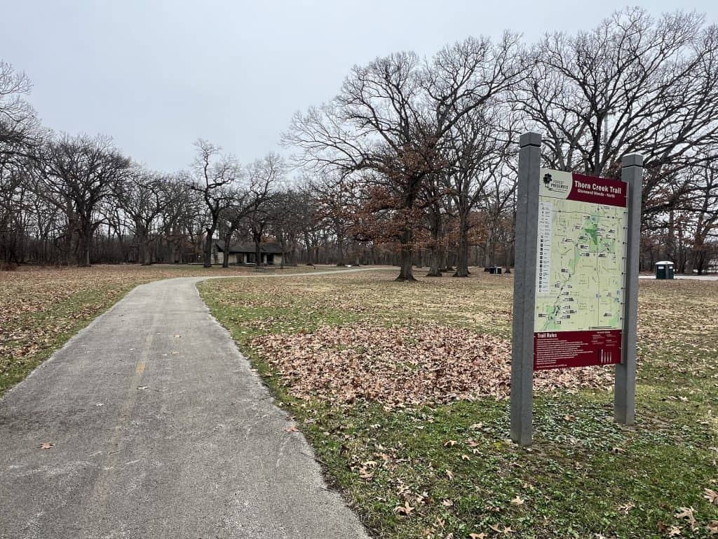 A scenic trail along Thorn Creek with park signage in suburban Chicago during fall.