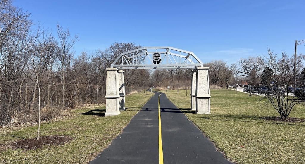A scenic view of the Cal-Sag Trail with a pedestrian bridge and clear blue sky.