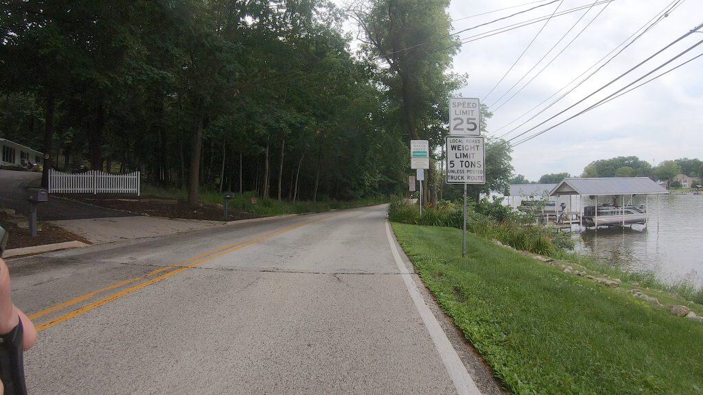Scenic road along a river with speed limit and weight limit signs in Barrington Hills.