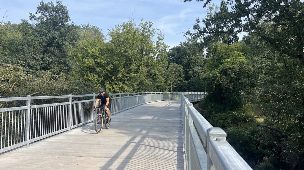 Cyclist riding on a scenic bridge surrounded by trees in suburban Chicago.