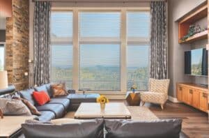 Sun shades window fashions with horizontal blinds and decorative curtains in a modern living room.
