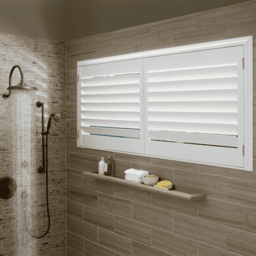 Luxurious white plantation shutters on bathroom window for privacy and style.