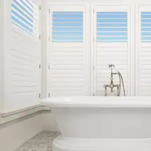 Elegant white window shades with adjustable louvers for bathroom privacy and light control.