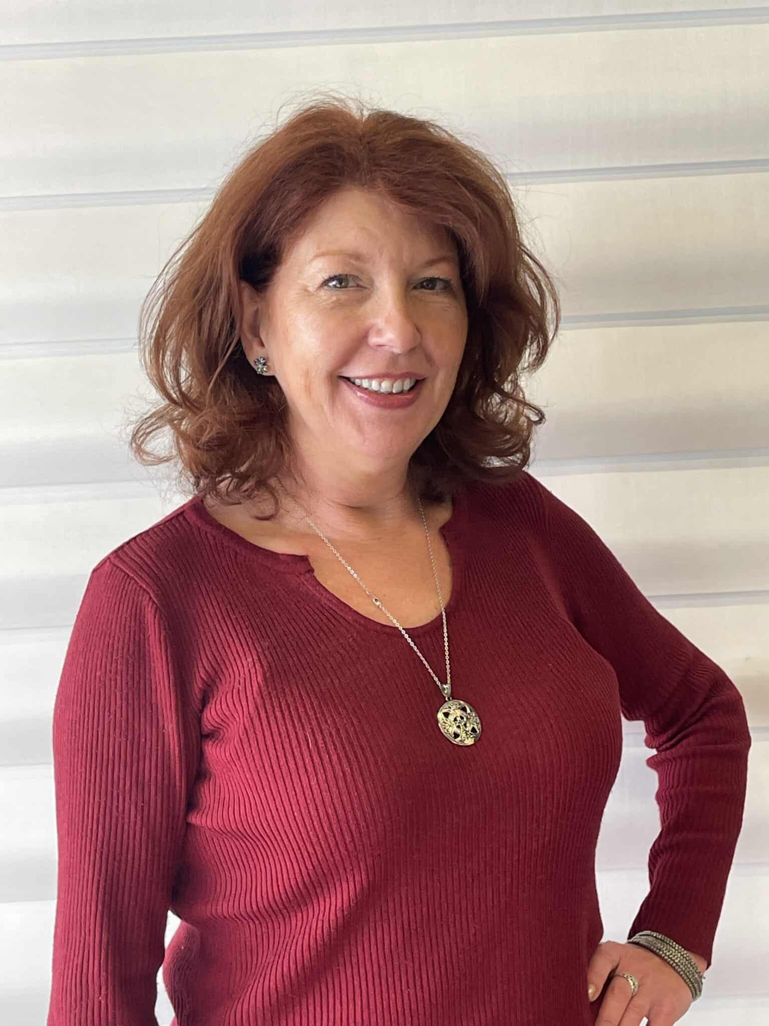 Bright woman smiling in front of window with sun shades, showcasing elegant window fashion and sun shade installation.