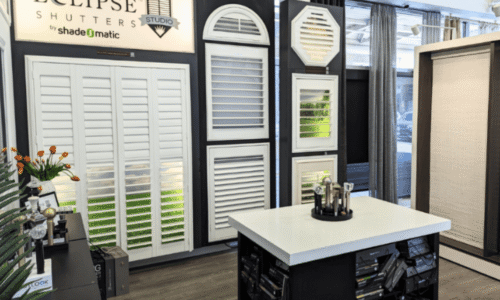 Showcase of various shutter styles including louvered, arched, and octagonal designs at Eclipse Shutters by Shadeomatic in a showroom setting.