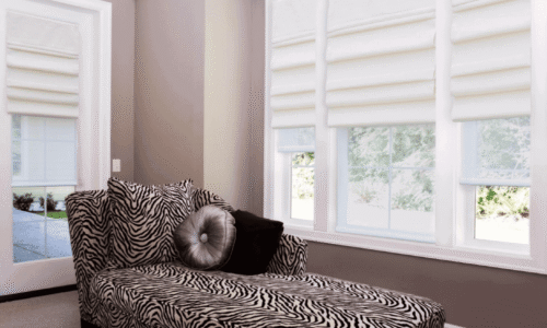 Zebra print lounge chair with black and gray cushions in a bright room with large windows and white blinds.