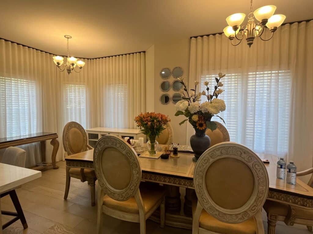 Soft white sun shades window fashions in a dining room, providing elegant light control and privacy with stylish, seamless curtains enhancing the space decor.