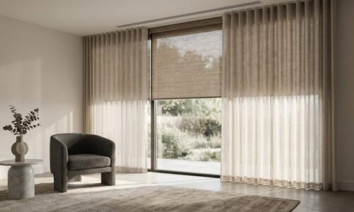 Bright living room with large floor-to-ceiling windows, sheer curtains, and a cozy armchair, overlooking a garden.