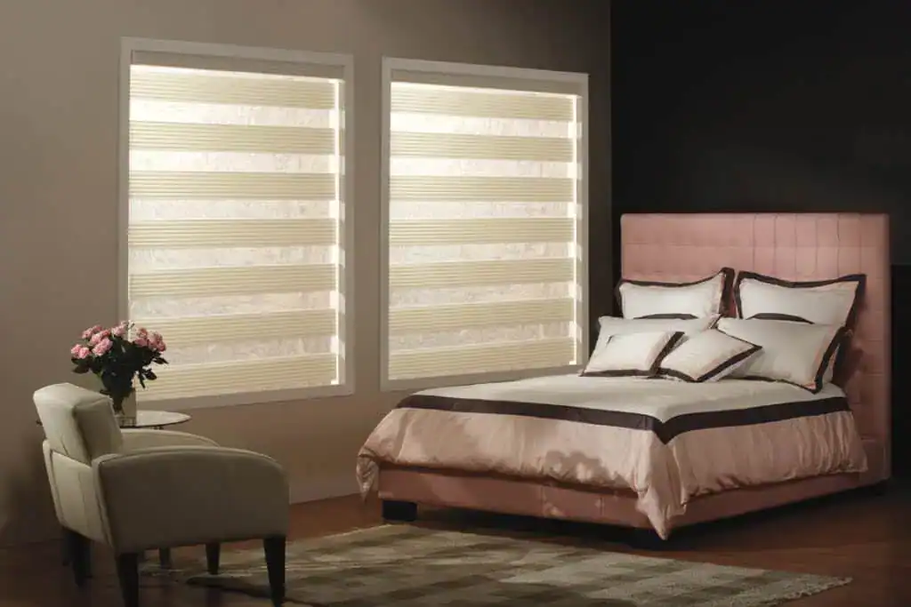 Bright bedroom featuring a pink upholstered bed, white bedding, and large windows with beige striped blinds.