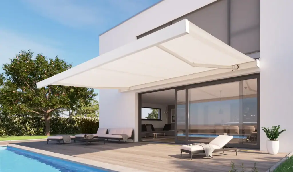 Contemporary outdoor patio with a large white retractable awning, lounge chairs, and a swimming pool, adjacent to a modern white house.