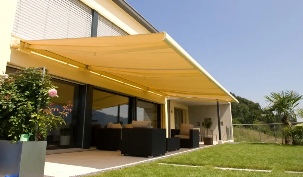 Contemporary outdoor patio with beige retractable awning, outdoor seating, and lush garden view, perfect for relaxing or entertaining.