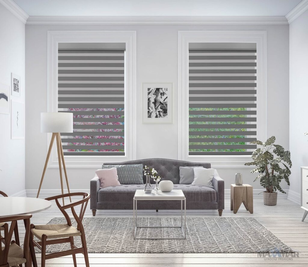 Bright living room featuring two large windows with double shades, a gray sofa, and minimalist decor.