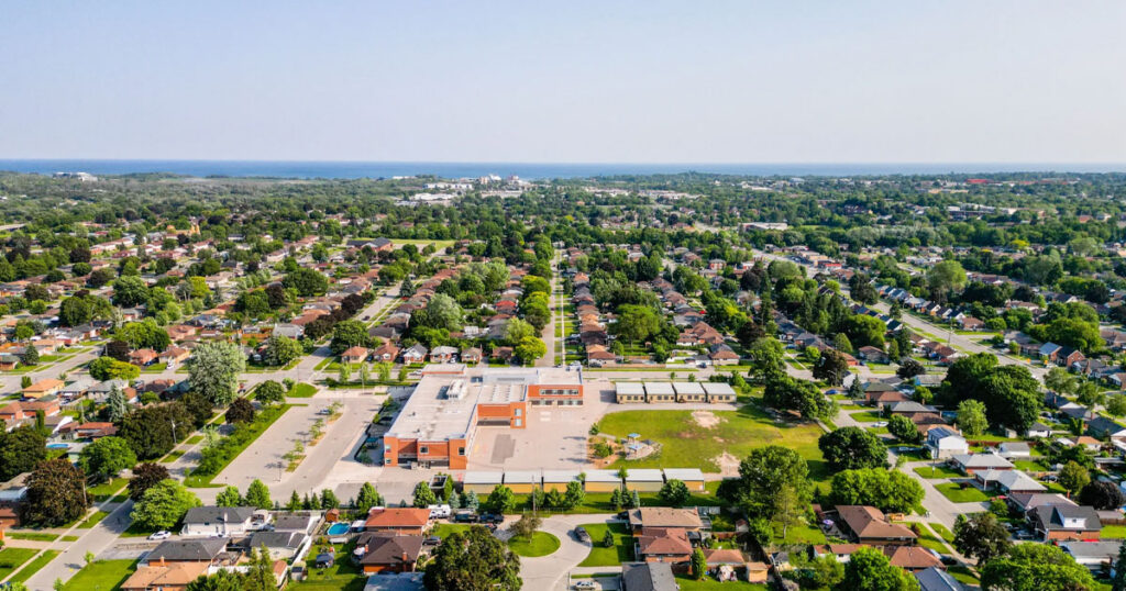 Aerial shot of Oshawa, Ontario showing residential neighborhoods, schools, and green spaces under a clear sky.