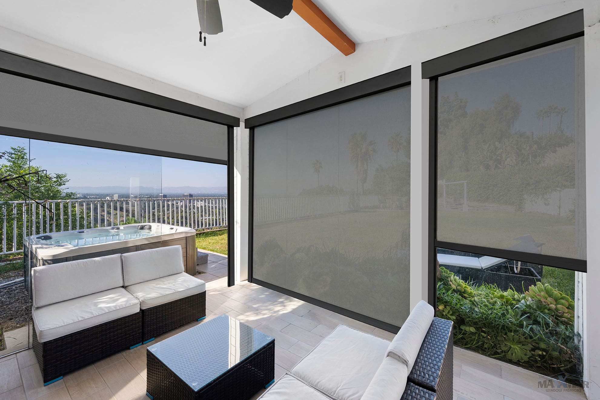 Contemporary outdoor patio with large roller shades, wicker furniture, and scenic view of greenery and sky.