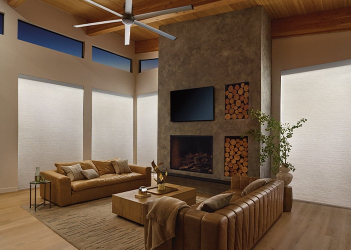 Luxury living room with custom superior blinds, modern fireplace, wood accents, and comfortable leather sofas, showcasing stylish window treatments for elegant home decor.
