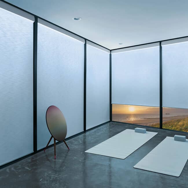 Modern interior with superior blinds on large windows, ocean view at sunset, minimalist decor ideal for relaxation and wellness, showcasing high-quality window coverings.