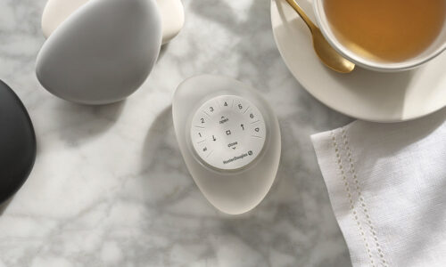Sleek modern egg-shaped smart home device on a marble surface with eggs and tea, showcasing innovative home automation solutions.