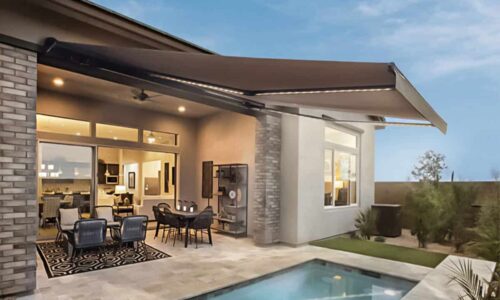 Modern outdoor patio with sleek retractable fabric awning, comfortable seating, and a sparkling pool, perfect for outdoor living and shade solutions from Superior Blinds.