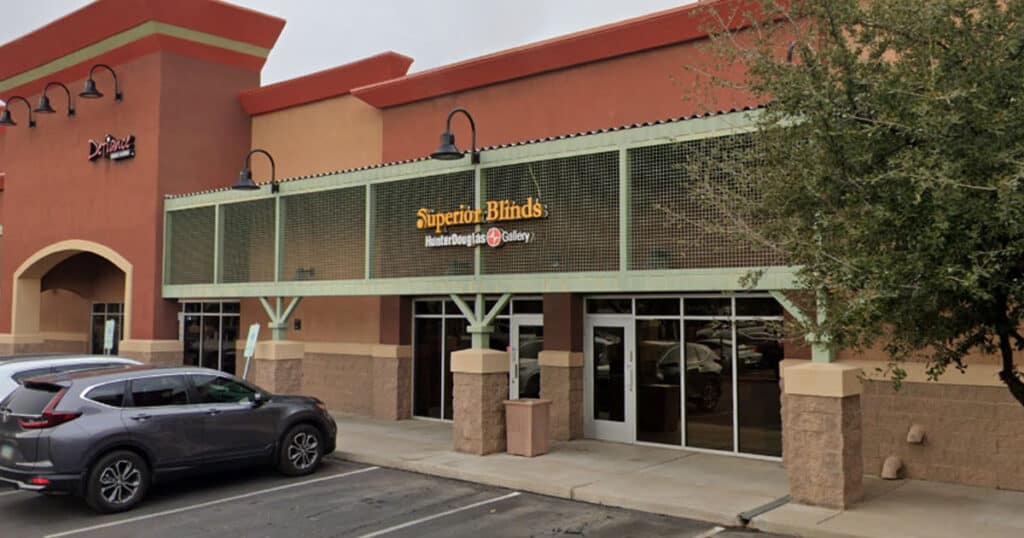 Modern exterior of Superior Blinds store with large glass windows, stylish signage, and parking area, showcasing quality window treatments and professional service in a commercial setting.