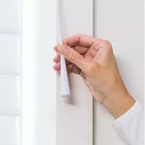Removable white window blind slats being adjusted, showcasing easy installation and maintenance of superior blinds.