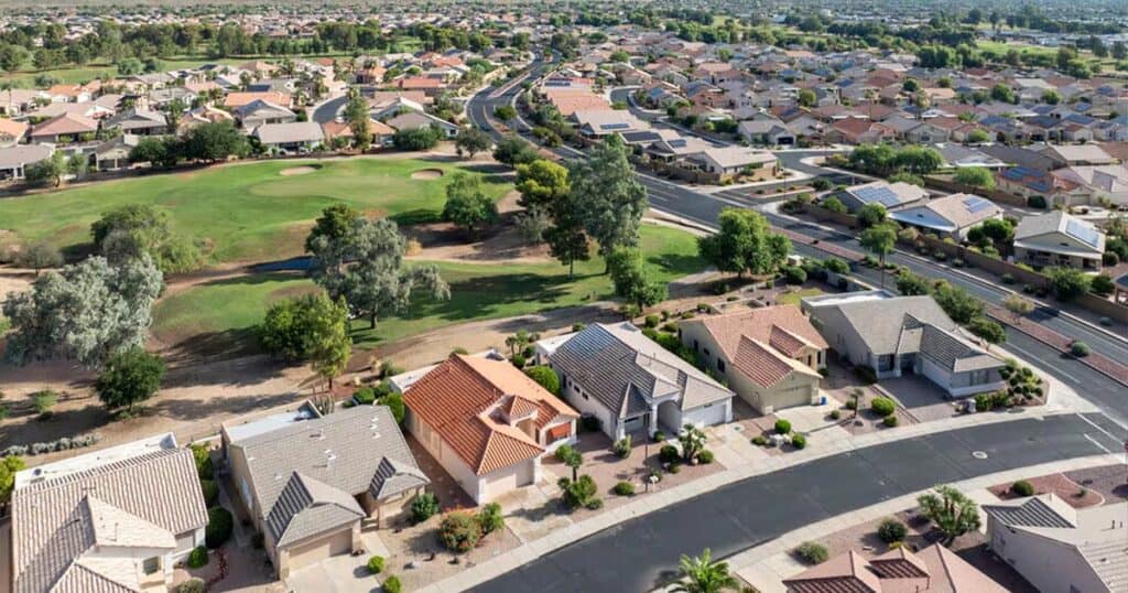 Bright aerial view of a suburban neighborhood with single-family homes near a lush golf course, showcasing the peaceful community atmosphere.
