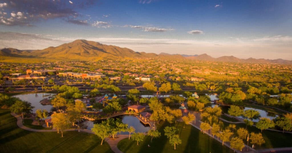 Mountain and lake view landscape during sunset, with lush greenery and a peaceful residential community under a vibrant sky. Perfect for showcasing beautiful views in window treatments.