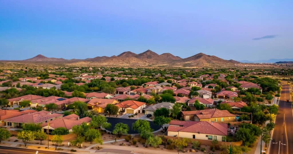 Elegant residential neighborhood with single-family homes, lush greenery, and scenic mountain backdrop; ideal for showcasing window blinds and home decor solutions.
