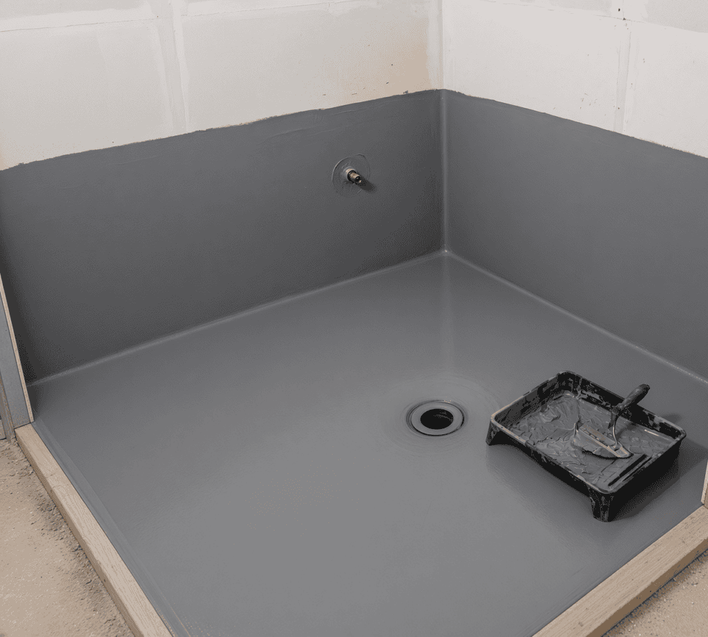 Waterproof membrane applied across a bathroom floor and up the lower walls during a wet room build, with a sealed junction around the drain and mixer points, before tiling.