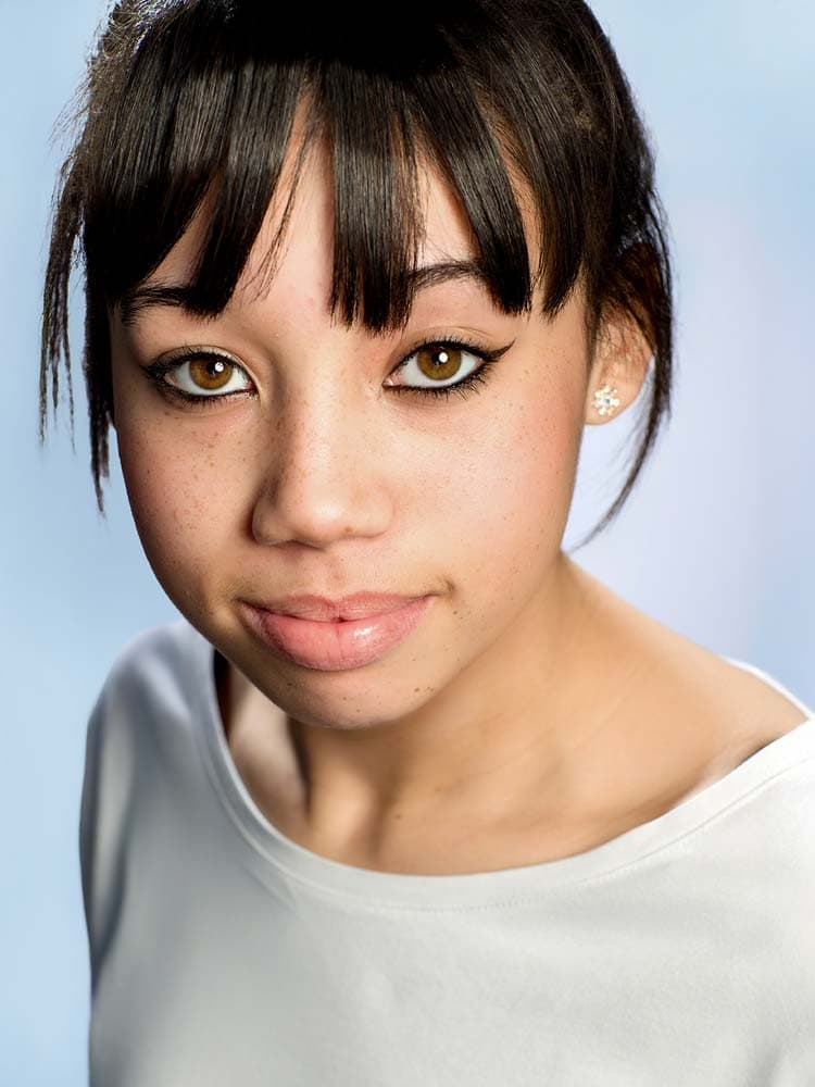 Vibrant headshot of young woman with dark hair and hazel eyes, professional Sussex portrait, perfect for business or acting profiles.